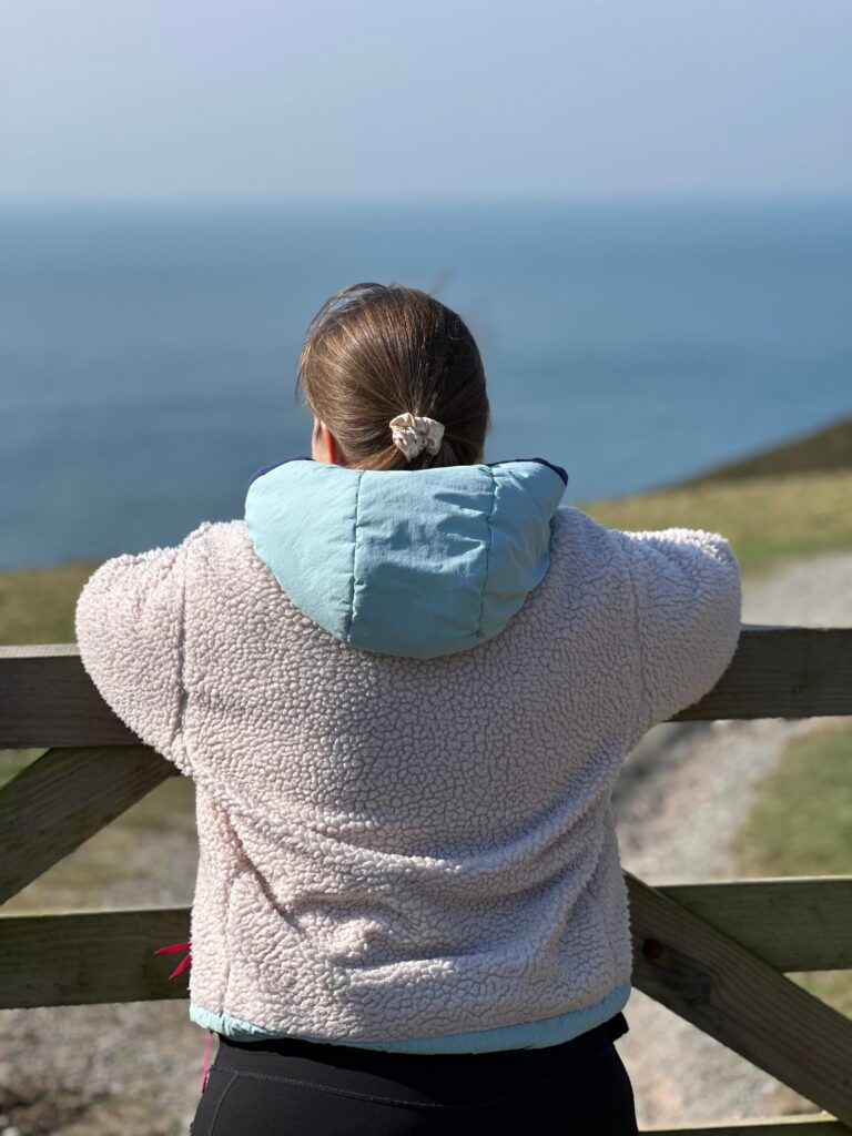 Woman looking out to sea from a coastal path on a spring day — female founder wellbeing, ERA Life First, life first always